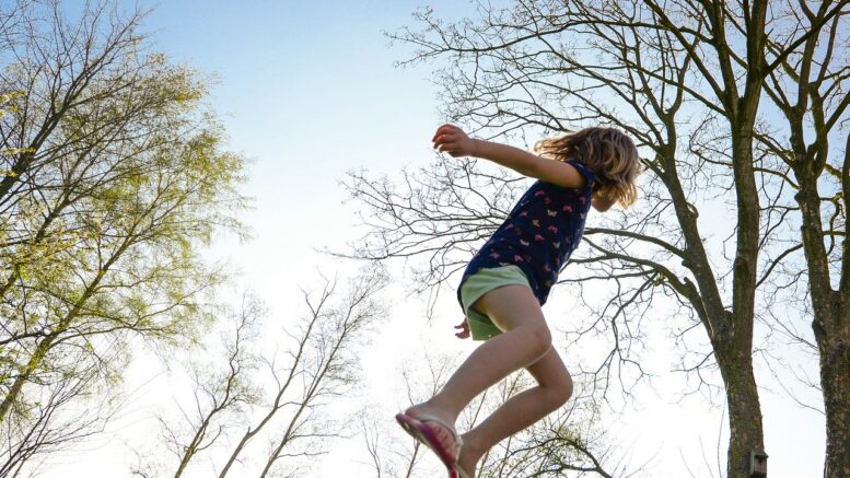 Pige hopper på trampolin udenfor om aftenen